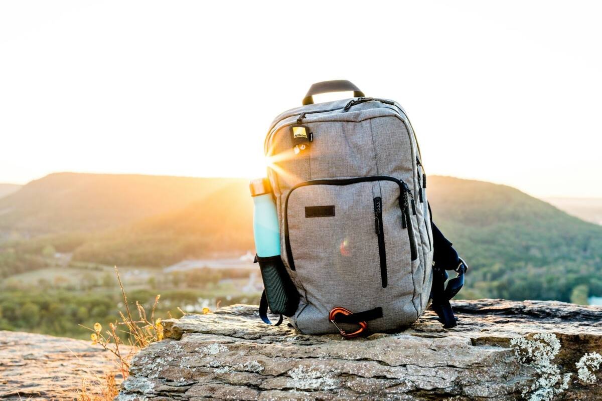 Hiking backpack and tumbler on a rock at sunset