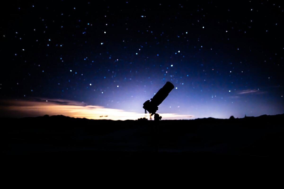 Telescope sitting on a hill under a night sky