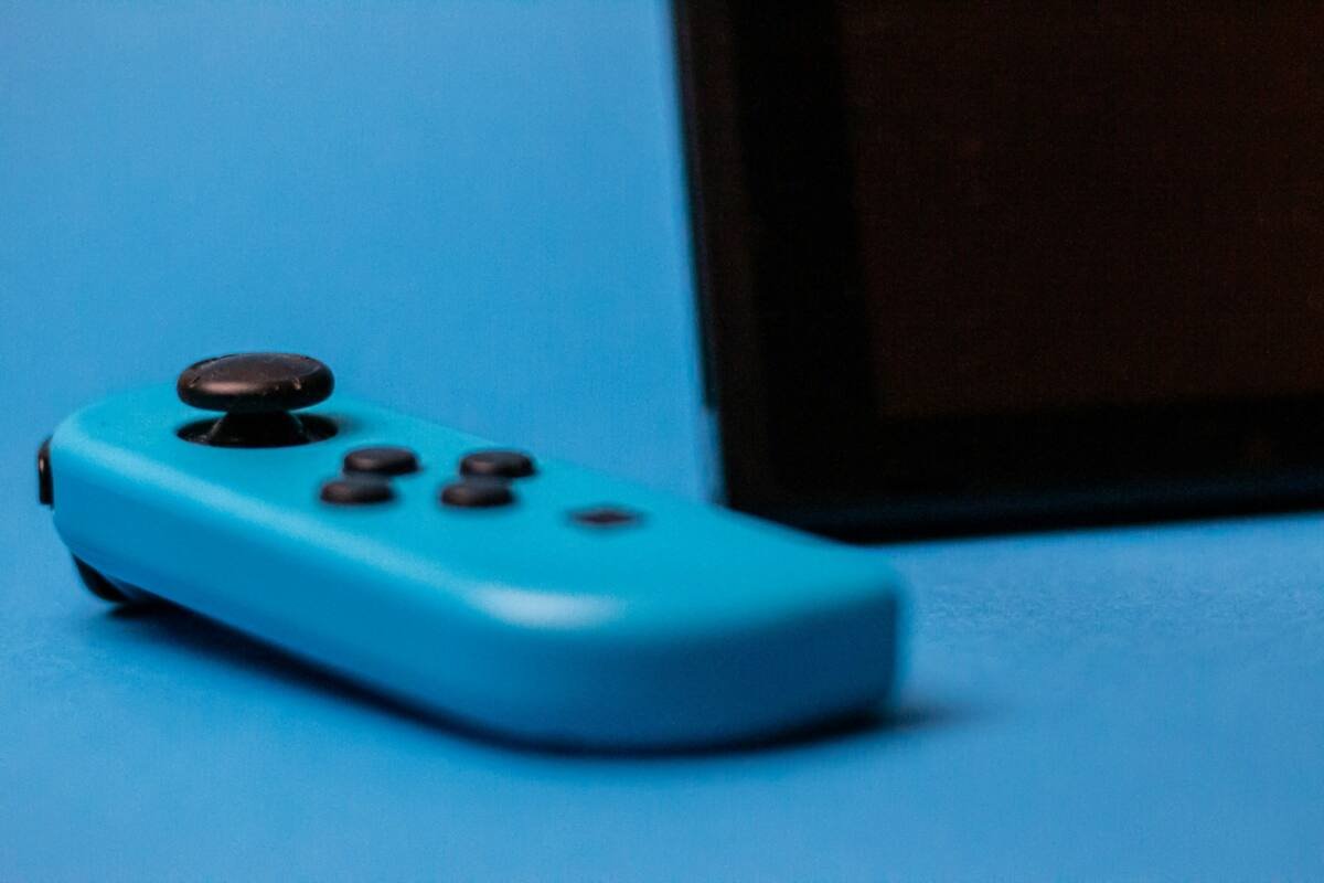 Blue Nintendo Switch controller with console in background