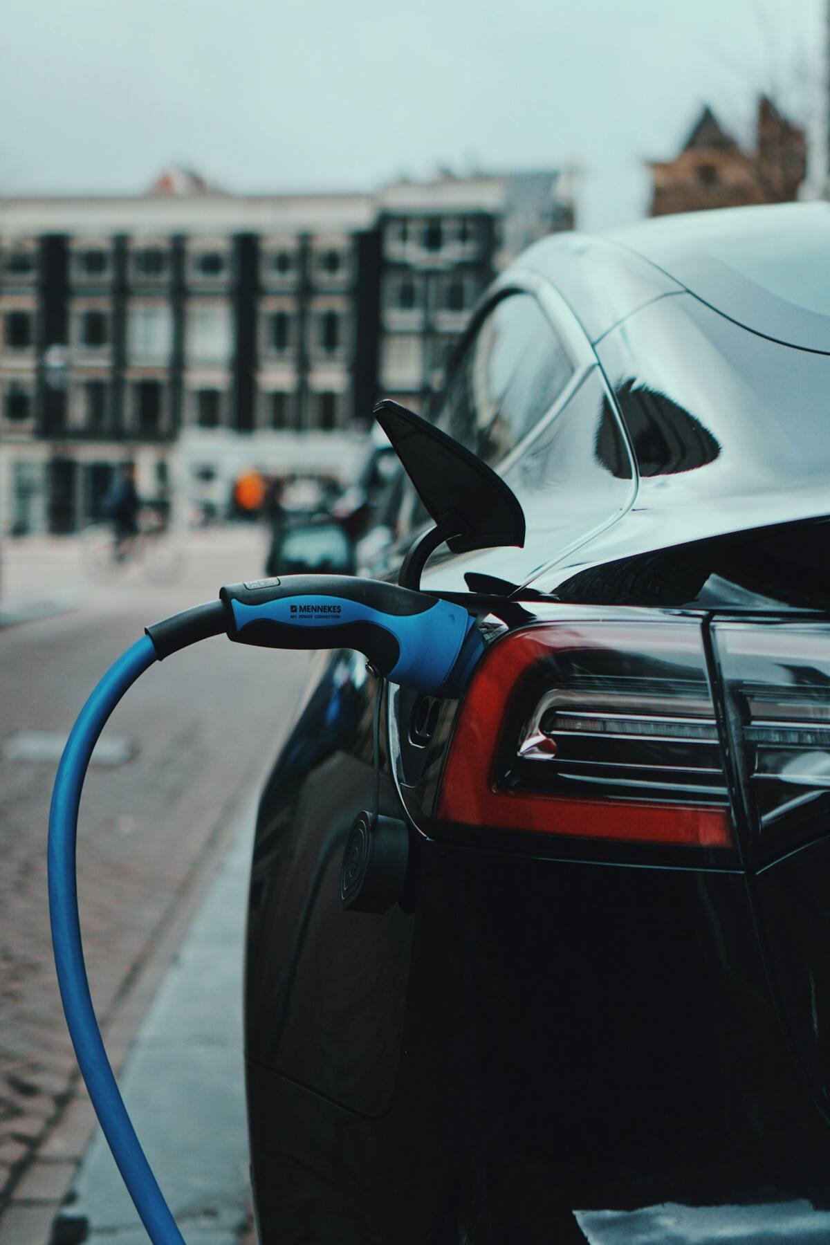 Black electric car charging on a city street
