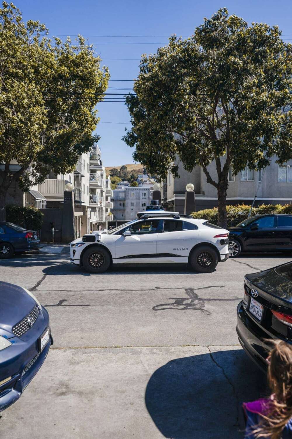 A white self-driving car on a city street
