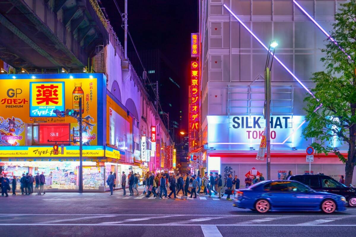 Tokyo street at night lit by neon signs, with pedestrians