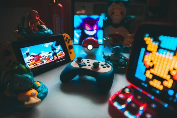 Handheld game console and controller on a desk among small figurines