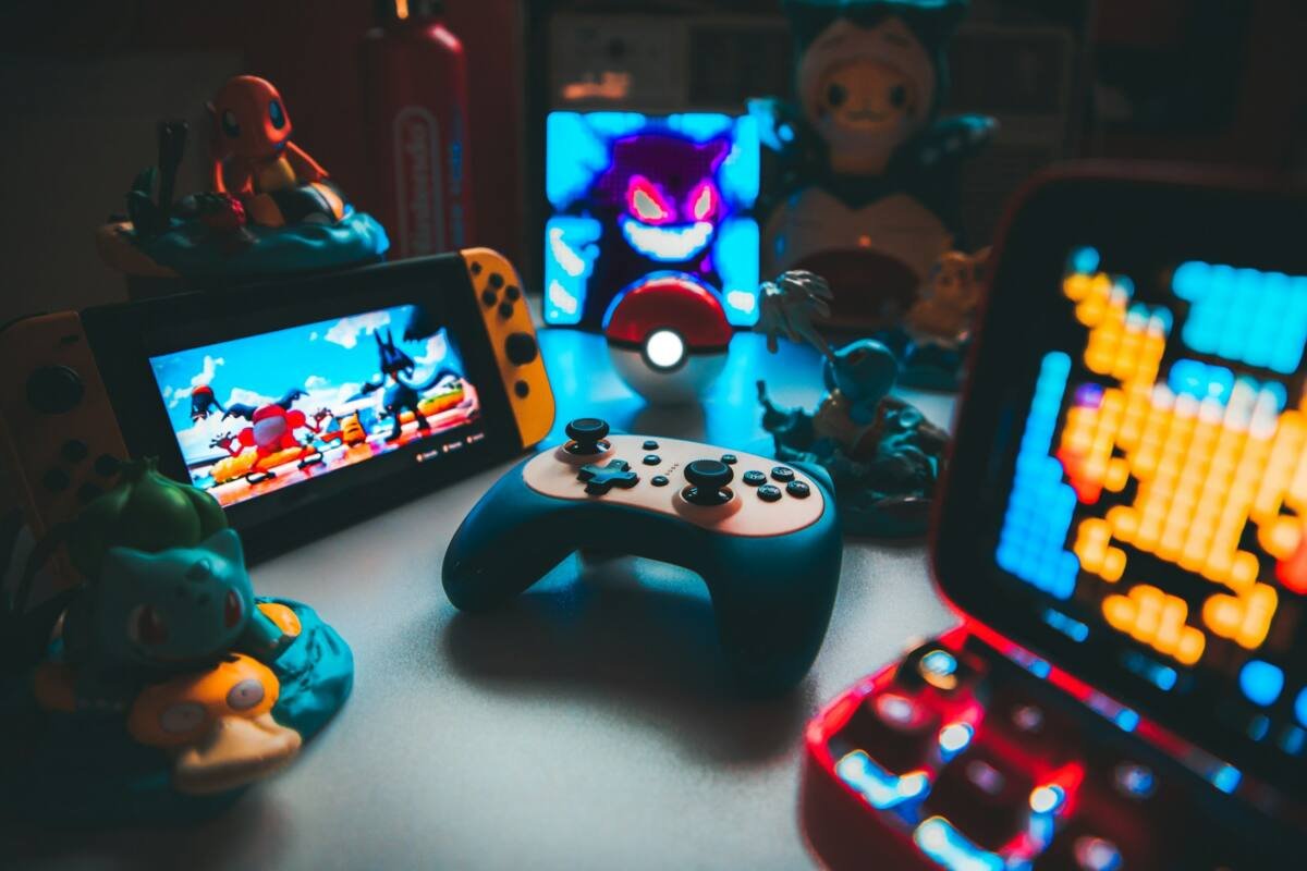 Handheld game console and controller on a desk among small figurines