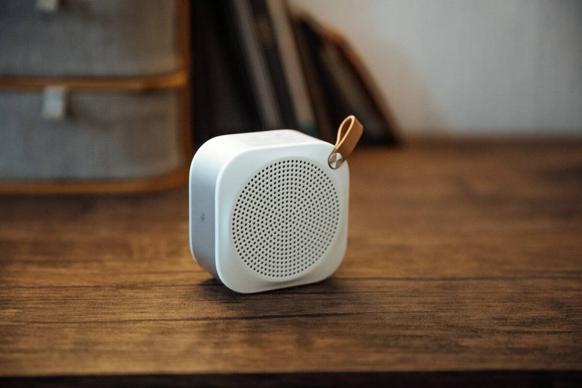 White and silver portable Bluetooth speaker on a wooden table