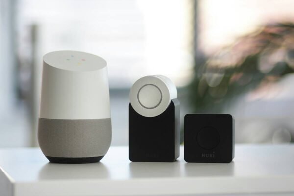 White and gray smart speaker next to two black speakers on a shelf