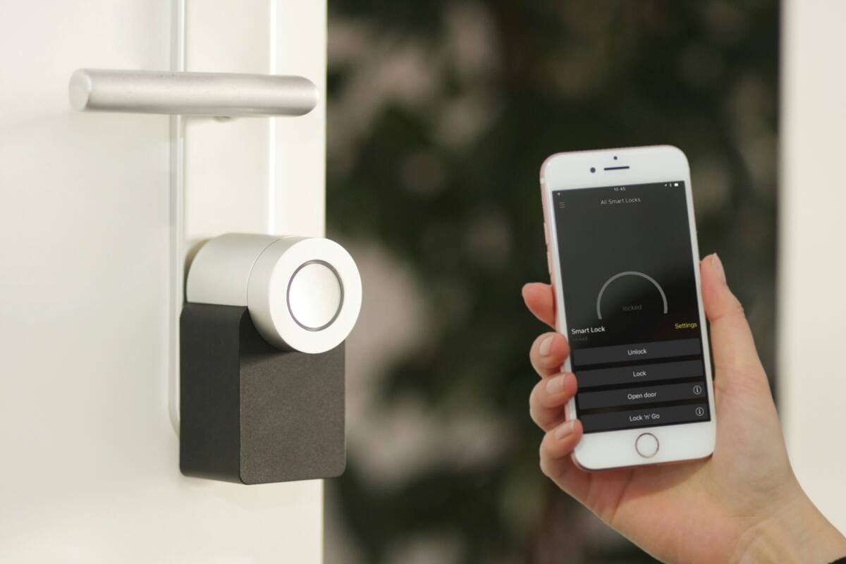 Smartphone held up at a front door to unlock a smart lock